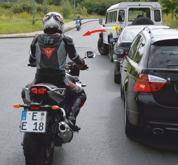 Motorradfahrer hinter Auto, das Wendemanöver startet.